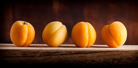 Apricots group lined up on wooden box and dark background