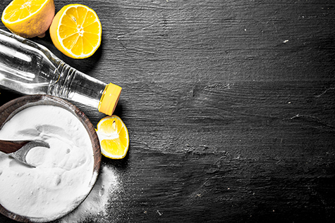 Baking soda in a bowl with vinegar and lemon slices.