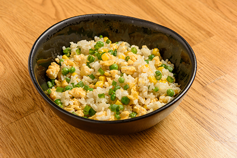 A bowl of fried rice on wooden table.