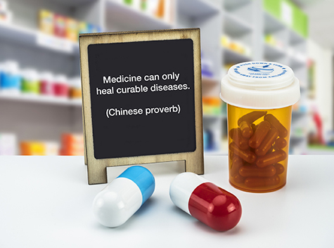 Informational Sign in a pharmacy, Medicine can only heal curable diseases. (Chinese proverb), on a whiteboard next to bottles of medicines, conceptual image