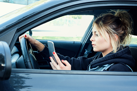 Woman driving car distracted by her mobile phone