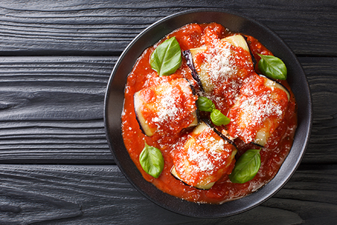 eggplant rolls stuffed with ricotta and baked in tomato sauce and served with parmesan and basil close-up in a plate. Horizontal top view
