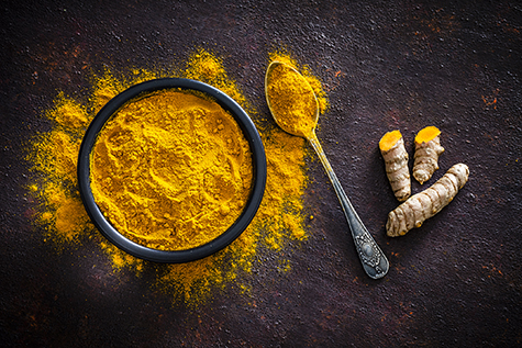 Spices: Turmeric roots and powder shot from above