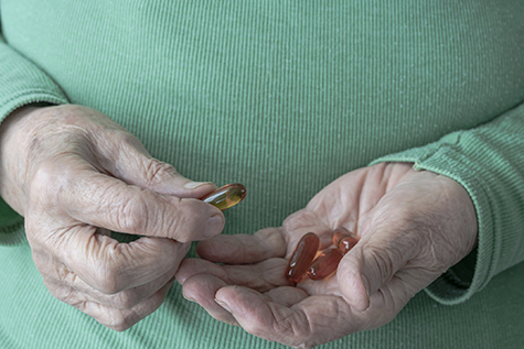 Hands of a senior woman holding vitamin pills on her palm