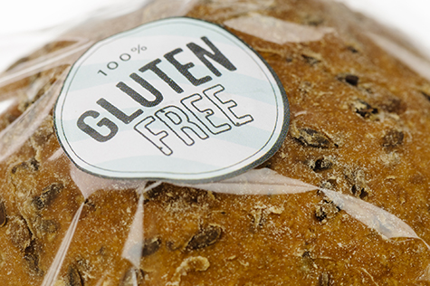 "100% Gluten Free" sticker on a loaf of brown seeded bread.