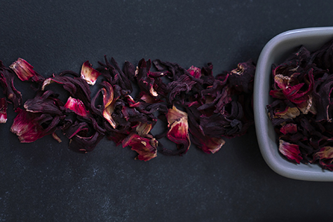 Large variety of multi colored dried tea leaves and flowers shot on white table