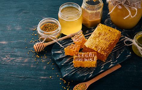 A set of honey and bee products. Honey in honeycomb. On a black wooden background. Free space for text. Top view.