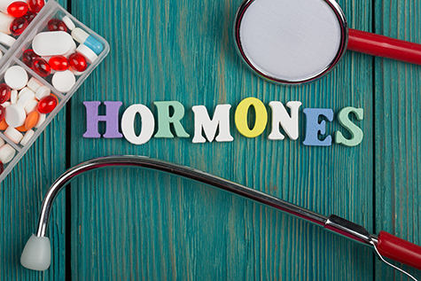 Text "Hormones" of colored wooden letters, stethoscope and pills