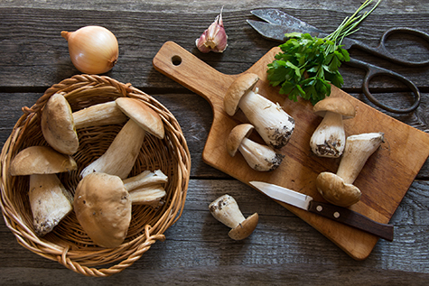 Fresh white mushrooms in basket on a rustic wooden board.