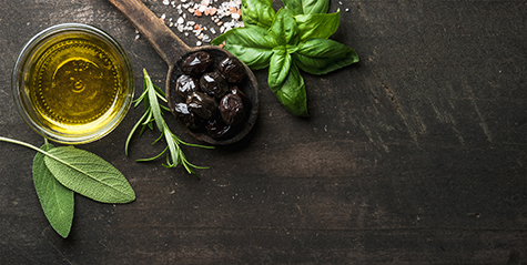 Greek black olives, fresh herbs and oil on dark rustic