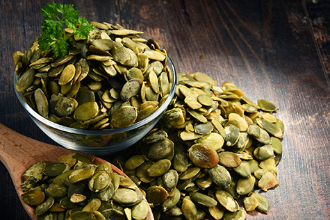 Composition with bowl of pumpkin seeds on wooden table
