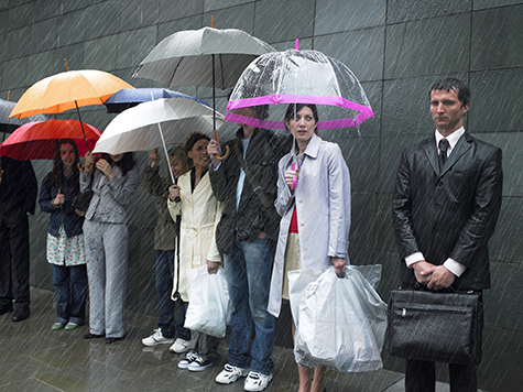 Soaked businessman standing beside group of people under umbrellas