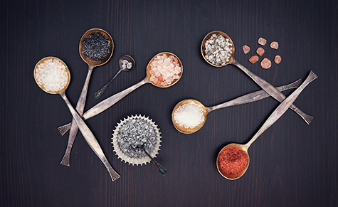 Assortment of salt in a metal spoon on a wooden