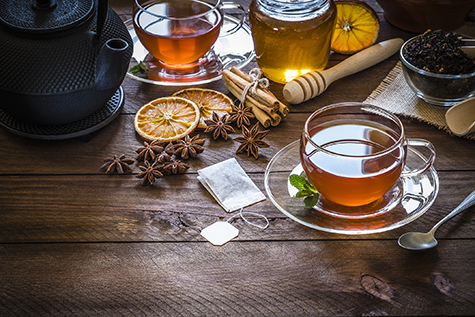 Tea time: cup of tea, cinnamon sticks, anise, dried orange on wooden table