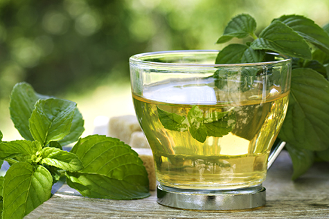 A glass of mint tea on a table covered in mint leaves