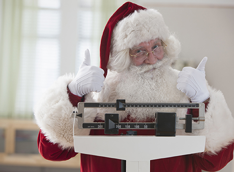 Santa Claus weighing himself with thumbs up
