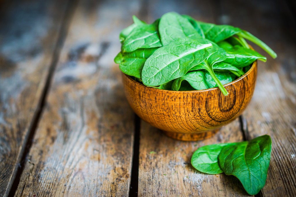Fresh spinach in a wooden bowl on a wooden table background
