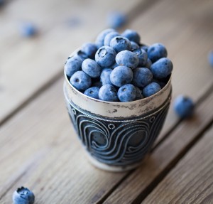 Old bowl of fresh organic blueberries on wooden table