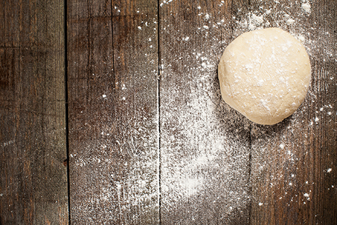 Ball of pizza dough on a rustic wooden background