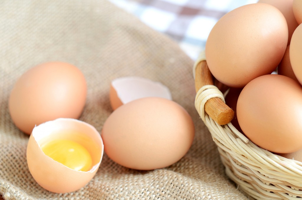 Basket with eggs and raw egg on a linen tablecloth
