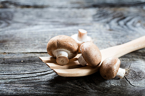 mushrooms on wooden salad fork on retro wood background
