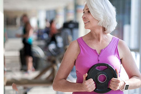 Delighted smiling woman exercising with sport equipment.