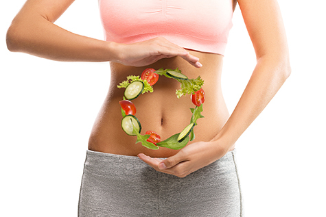 Fit, young woman holding a circle made out of vegetables over her abdomen