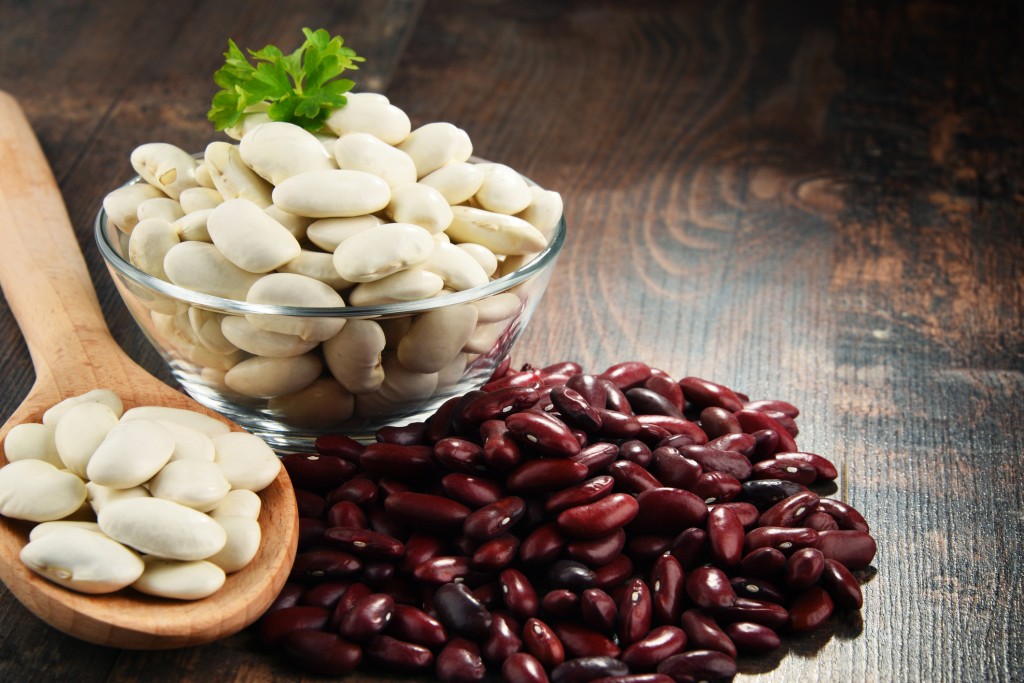 Composition with bowl of beans on wooden table