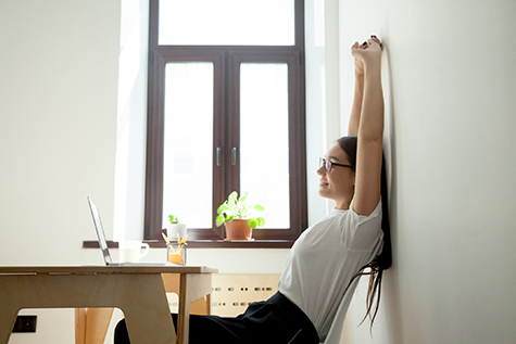 Attractive young businesswoman relaxing, stretching at desk in home office