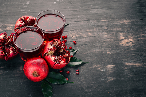 Fresh pomegranate juice. Pomegranate. On a black wooden background. Top view. Copy space.