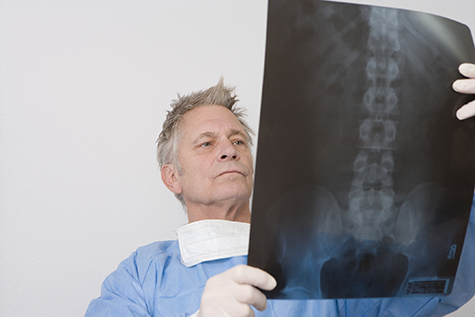 Senior medical practitioner stands with xray